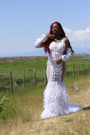 Model wearing LYNA white full-length dress with ruffle details and sheer side panels